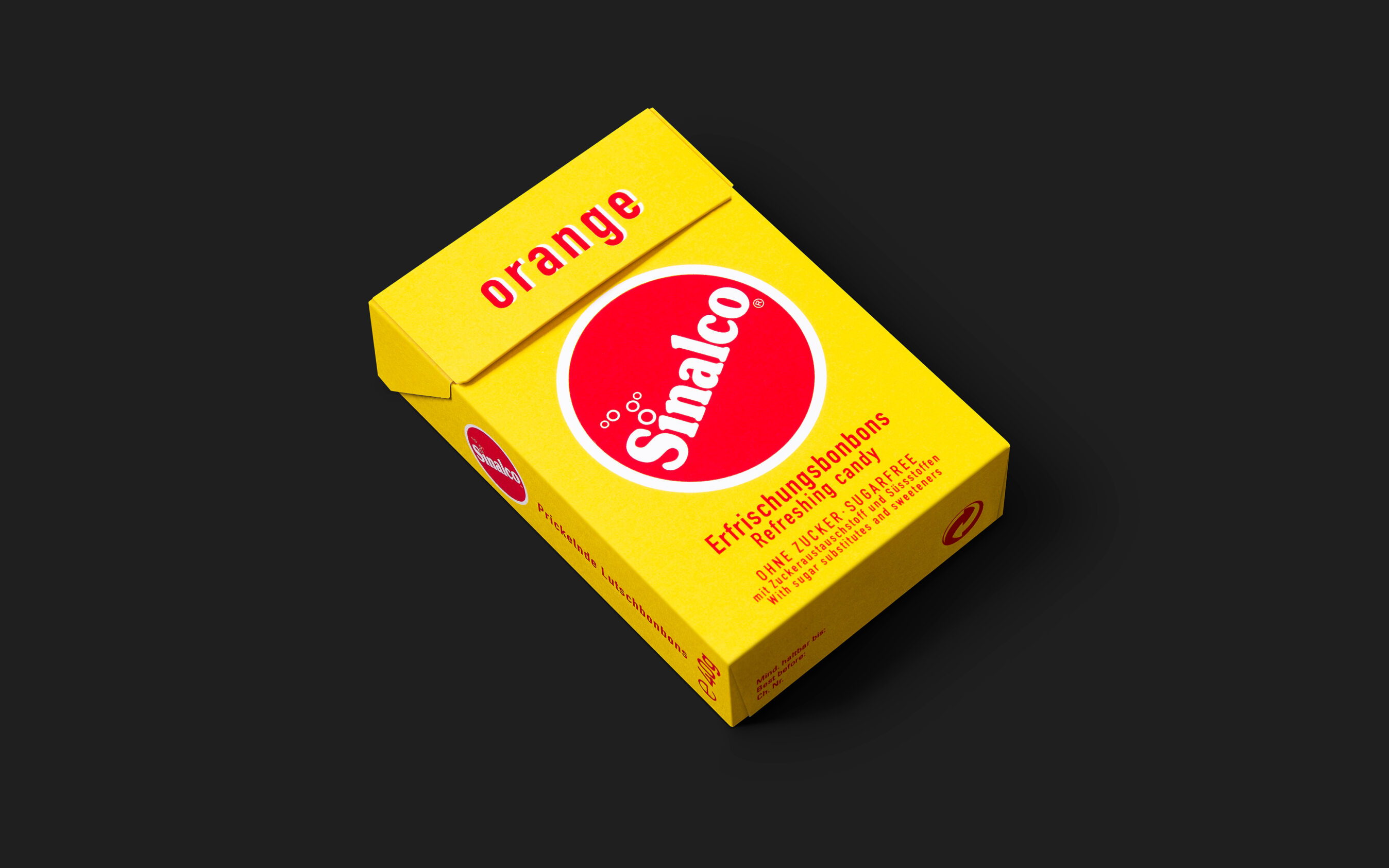 Die gelbe Bonbon-Schachtel liegend auf Schwarzem Hintergrund. Gestaltet von Grafikdesign Cueni Basel.